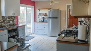 Eine moderne Küche mit weißen Schränken, einem Edelstahl-Kühlschrank, einem Gasherd und einem Deckenventilator.