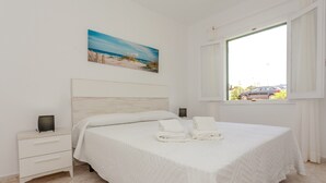 A bedroom with a bed, nightstands, a painting, and a window with a view.