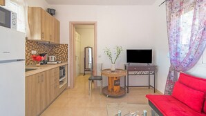Un espai habitable reduït amb cuina, zona de menjador i un sofà vermell.