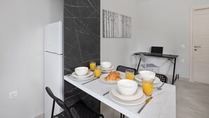 A dining area with a white table set for breakfast, including plates, bowls, croissants, and orange juice.