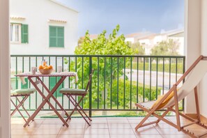 Un balcon avec une table, des chaises et un transat.
