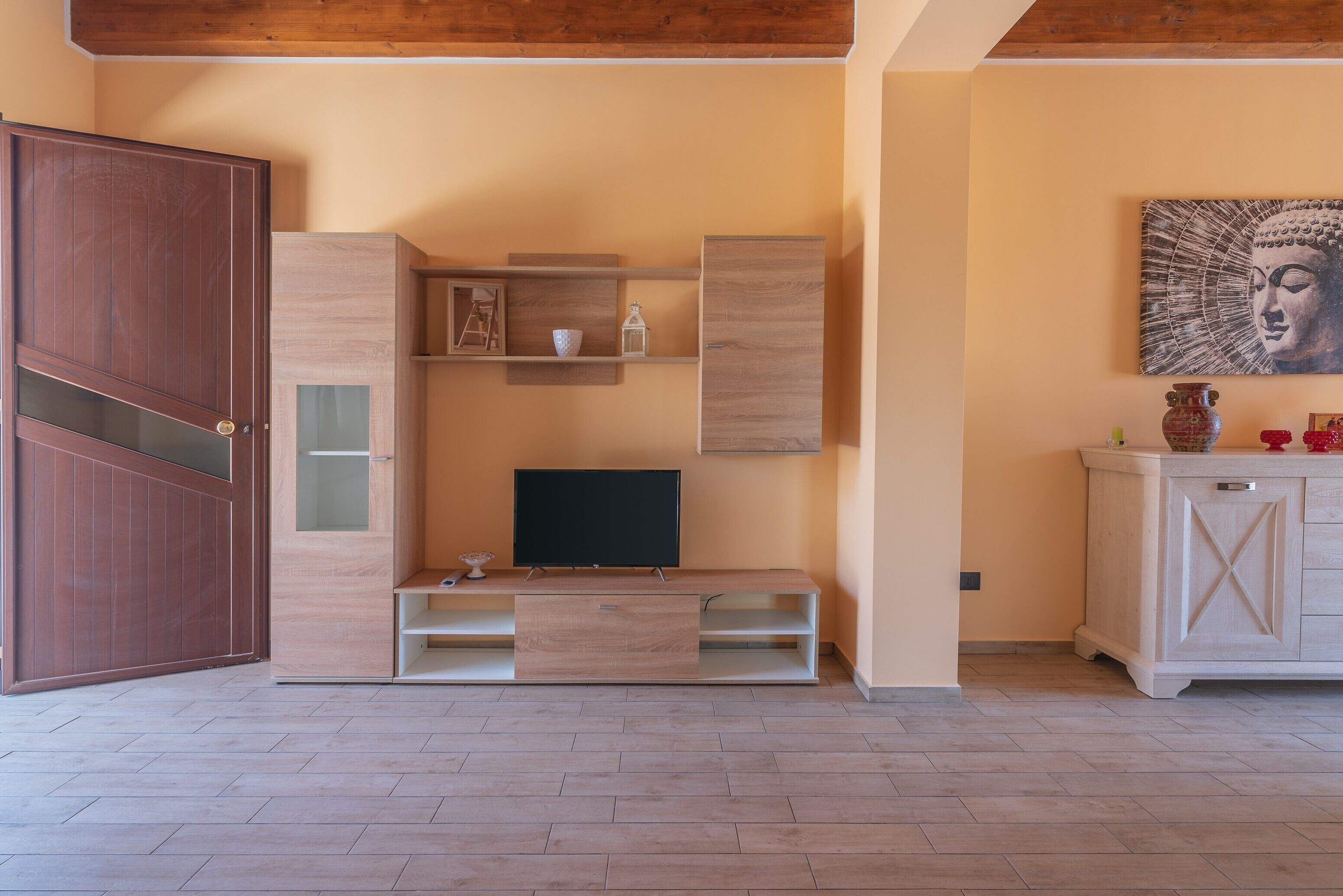 Ein Zimmer mit einer Holztrennwandschrank, einem Fernseher und einem Buddha-Gemälde an der Wand.