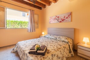 A bedroom with a large bed, a window with a view, a nightstand with a lamp, and a painting on the wall. - Holiday Home 'Brucoli Mare 1' with Sea View, Terraces & A/C (Brucoli)