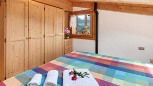 Un dormitorio con colcha a cuadros, armario de madera y ventana con vistas.