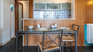 A compact kitchen with wooden cabinets, a tiled backsplash, and a dining table set with plates and bowls.
