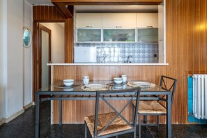 Una cocina compacta con armarios de madera, salpicadero de azulejos y una mesa de comedor con platos y tazones.
