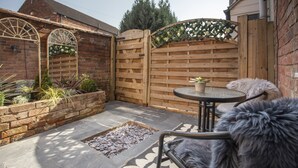 Une terrasse avec une porte en bois, une table ronde et une chaise.