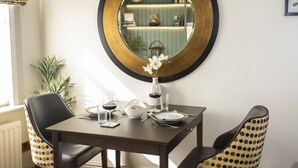 Une table à manger avec des chaises, un vase rempli de fleurs et un miroir accroché au mur.