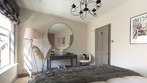 Une chambre à coucher avec un grand lit, un bureau, une chaise, un miroir et un lustre.