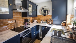 Une cuisine moderne avec des meubles de couleur sombre, un îlot central et un four encastré.