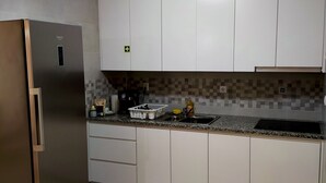 Una cocina moderna con armarios blancos, un refrigerador de acero inoxidable y salpicadero de azulejos.