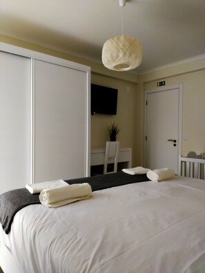 Ein Hotelzimmer mit einem großen Bett, einem Schreibtisch, einem Sessel, einem an der Wand montierten Fernseher und einer Tür mit einem Schild darüber.