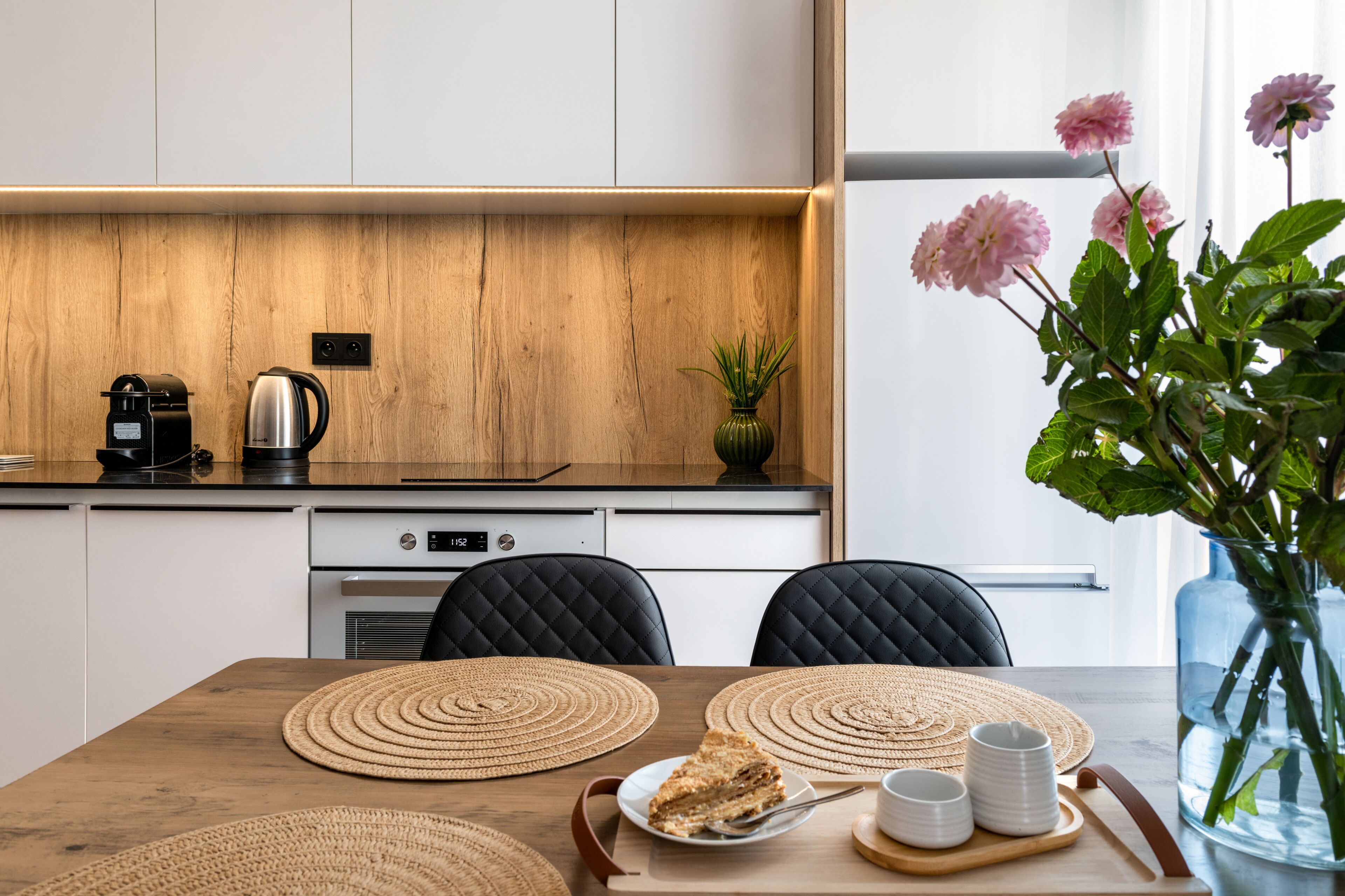 Et moderne køkken med en træbordplade, kaffemaskine og en vase med blomster.