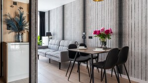 A modern dining area with a wooden table, black chairs, and a vase of flowers. - InPoint Cracow - Serviced Apartments G15 (Kraków)