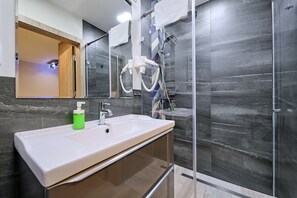 A modern bathroom with a white sink, a glass shower enclosure, and a mirror with a wooden frame. - InPoint Cracow - Serviced Apartments G15 (Kraków)