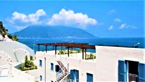 Ein Küstengebäude mit Blick auf das Meer und einem Berg im Hintergrund.