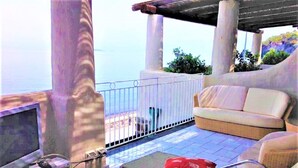 Ein Balkon mit einer Couch, einem Sessel und einem kleinen Tisch mit einem Computer.
