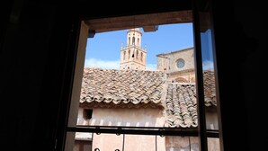 A view through a window of a building with a tiled roof and a bell tower.