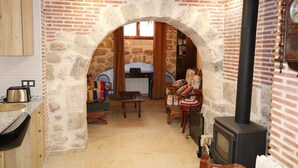 A cozy room with a stone archway leading to a dining area, a fireplace, and a television.