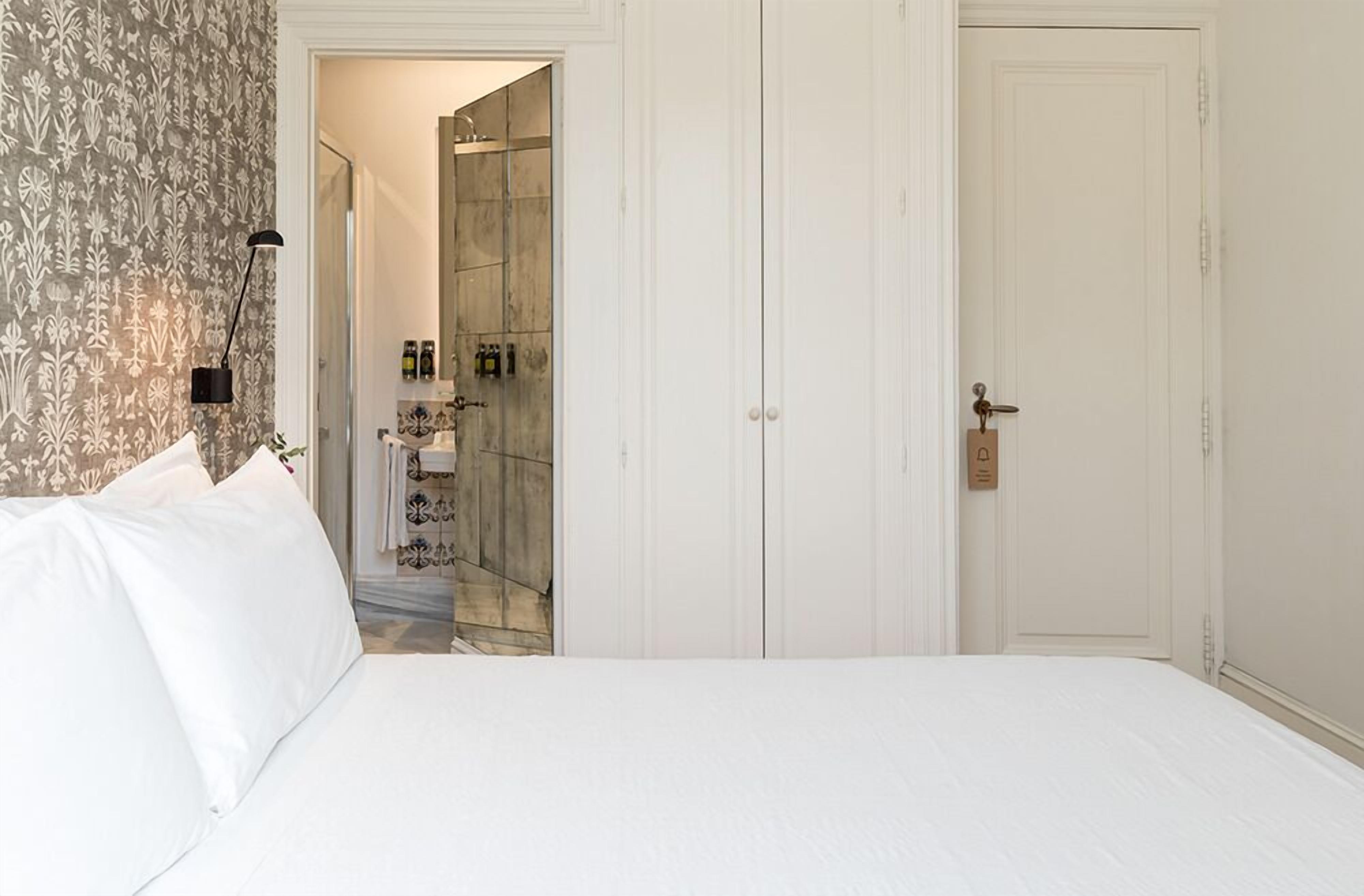 Habitación de hotel con cama, armario y baño visible a través de una puerta abierta.