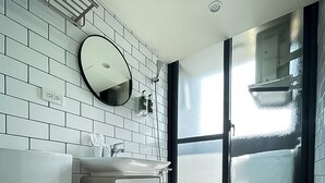 A modern bathroom with a white toilet, a sink, and a mirror. The floor has a geometric tile pattern. - Affetto hostel (Taichung)