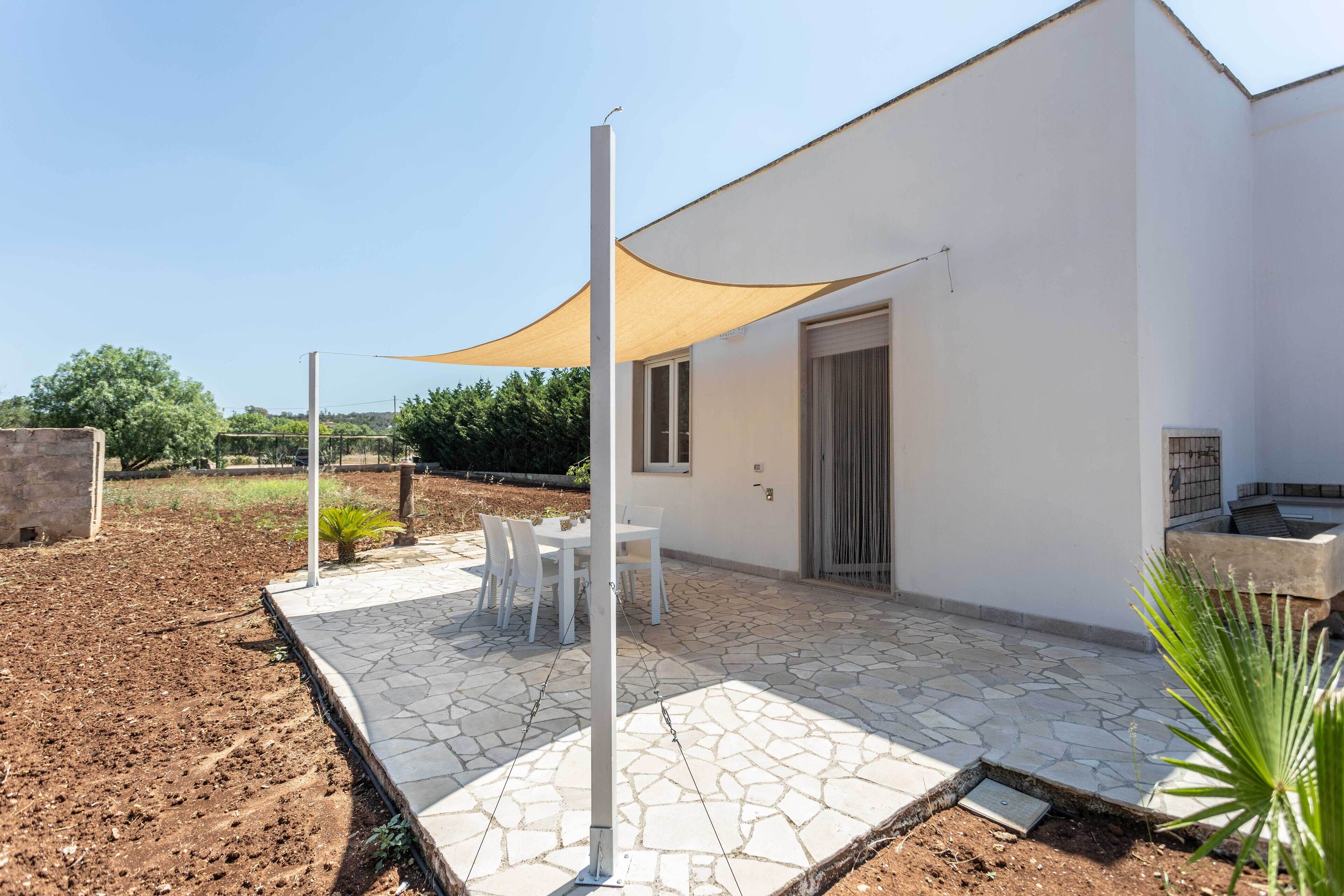 A modern house with a patio, white exterior, and a covered seating area.