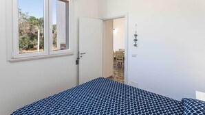 Ein Schlafzimmer mit einem Bett, einem Fenster und einer Tür, die in einen Essbereich führt.