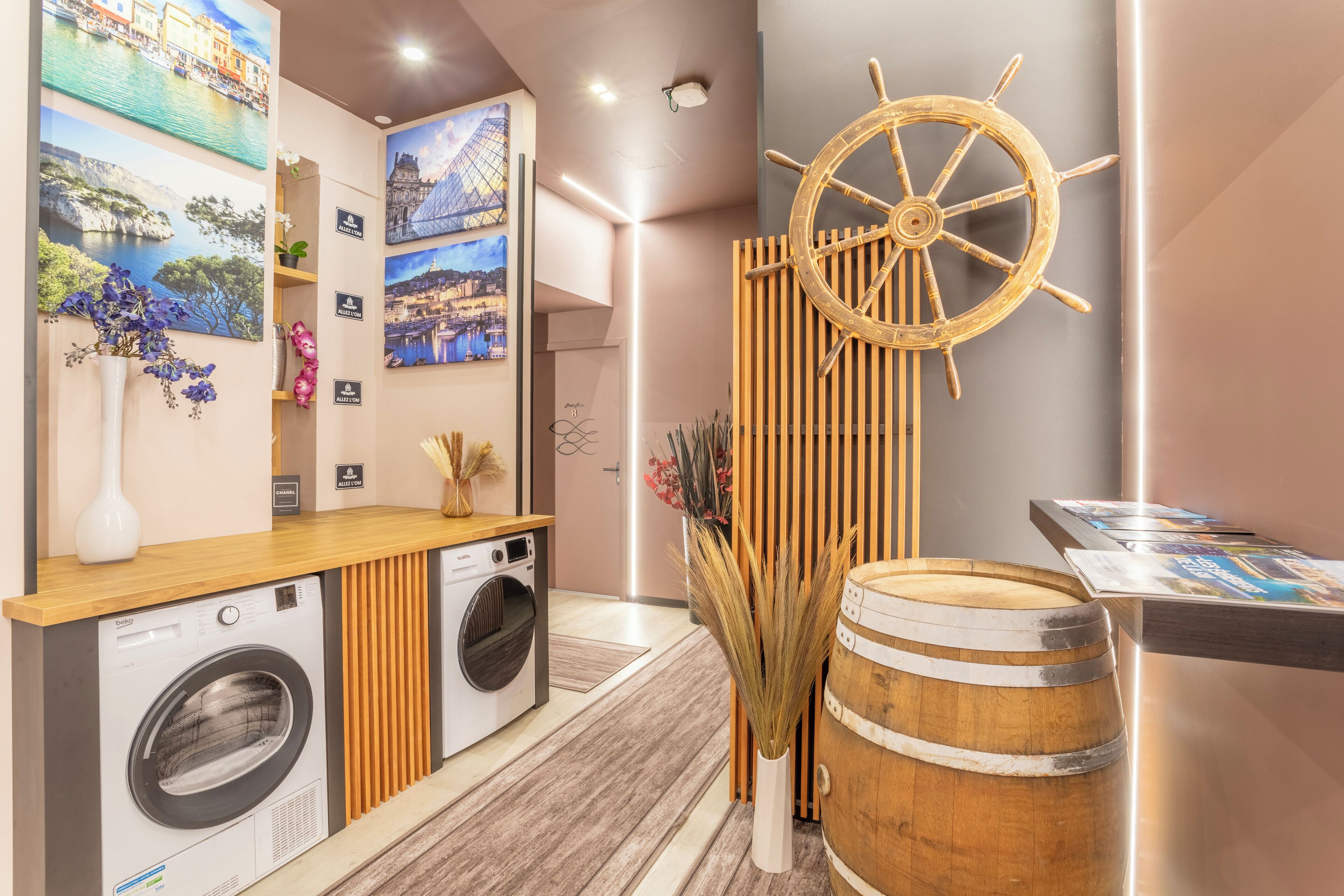 Een hotel receptie met een houten balie, een wasmachine, een decoratief wiel en ingelijste foto's aan de muur.
