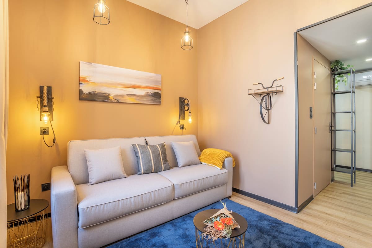 Una sala de estar moderna con un sofá, una mesa de centro, luces fijadas a la pared y un cuadro.