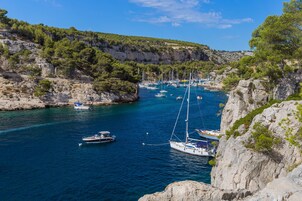 A coastal marina with boats docked, surrounded by rocky cliffs and greenery.