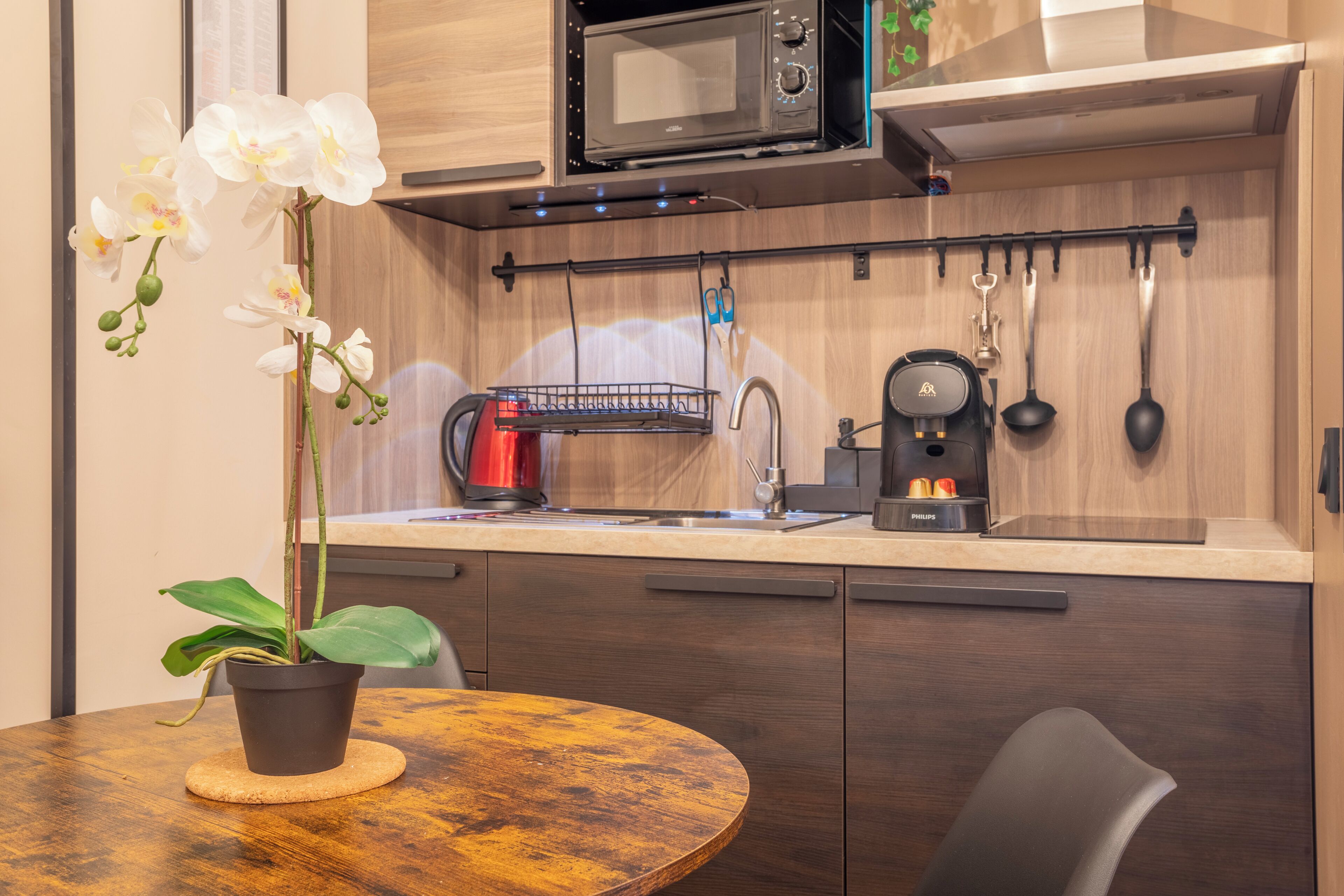 A modern kitchen with a microwave, coffee maker, and hanging utensils.