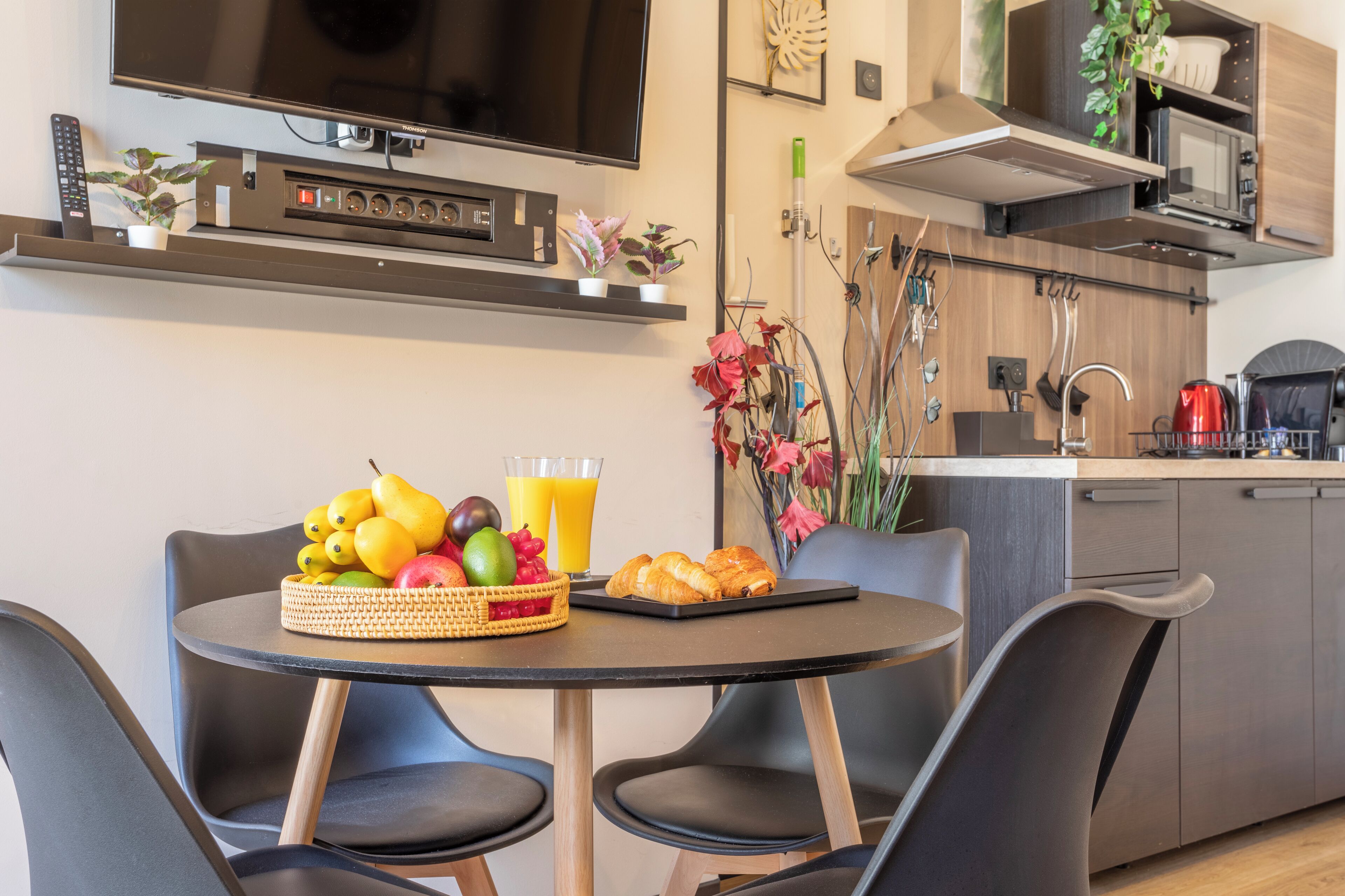 A modern kitchen with a dining area, including a TV, microwave, and various appliances.
