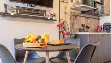 Una cocina moderna con comedor, que incluye un televisor, microondas y varios electrodomésticos.