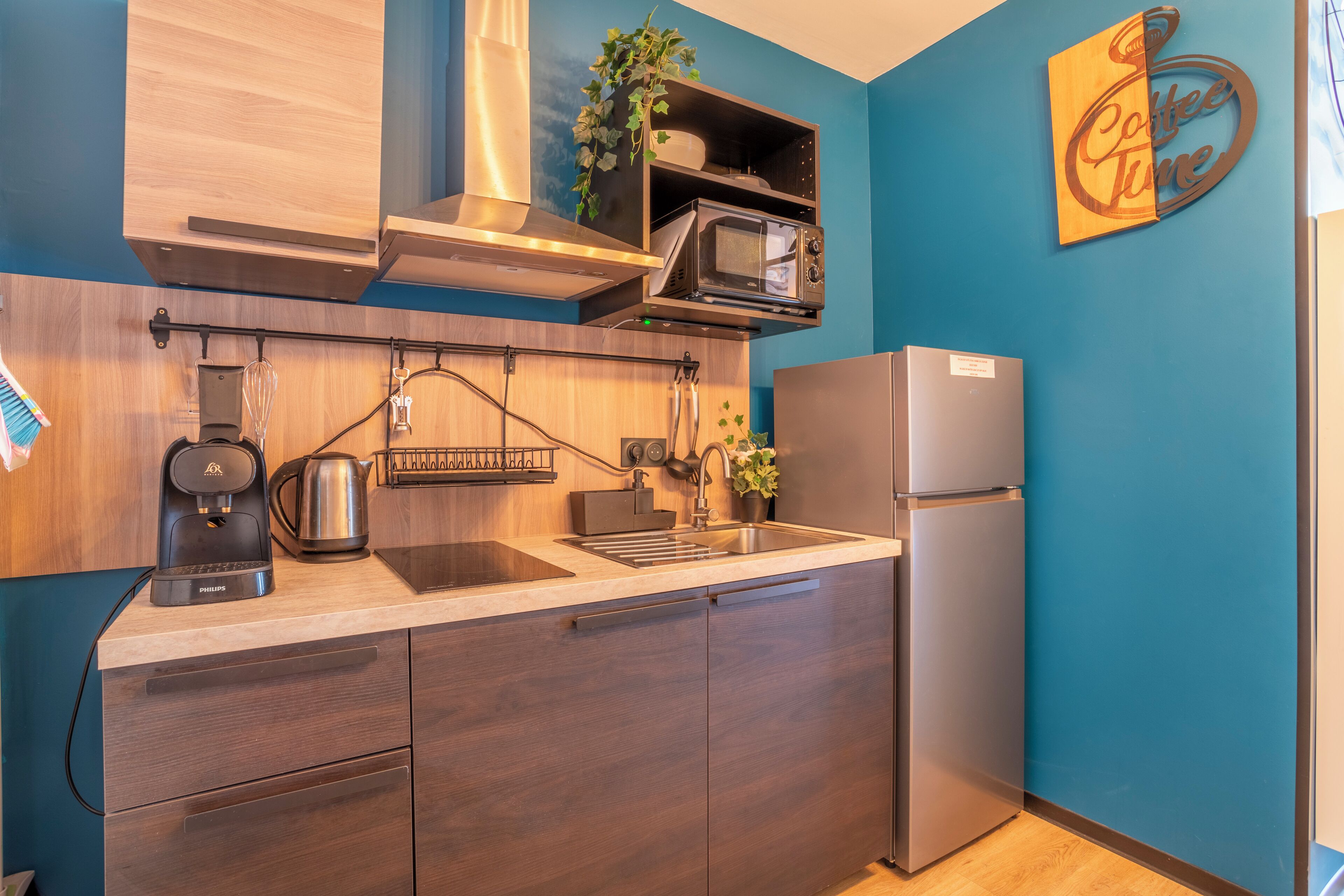 Una cocina moderna con microondas integrado, cafetera y un refrigerador de acero inoxidable.
