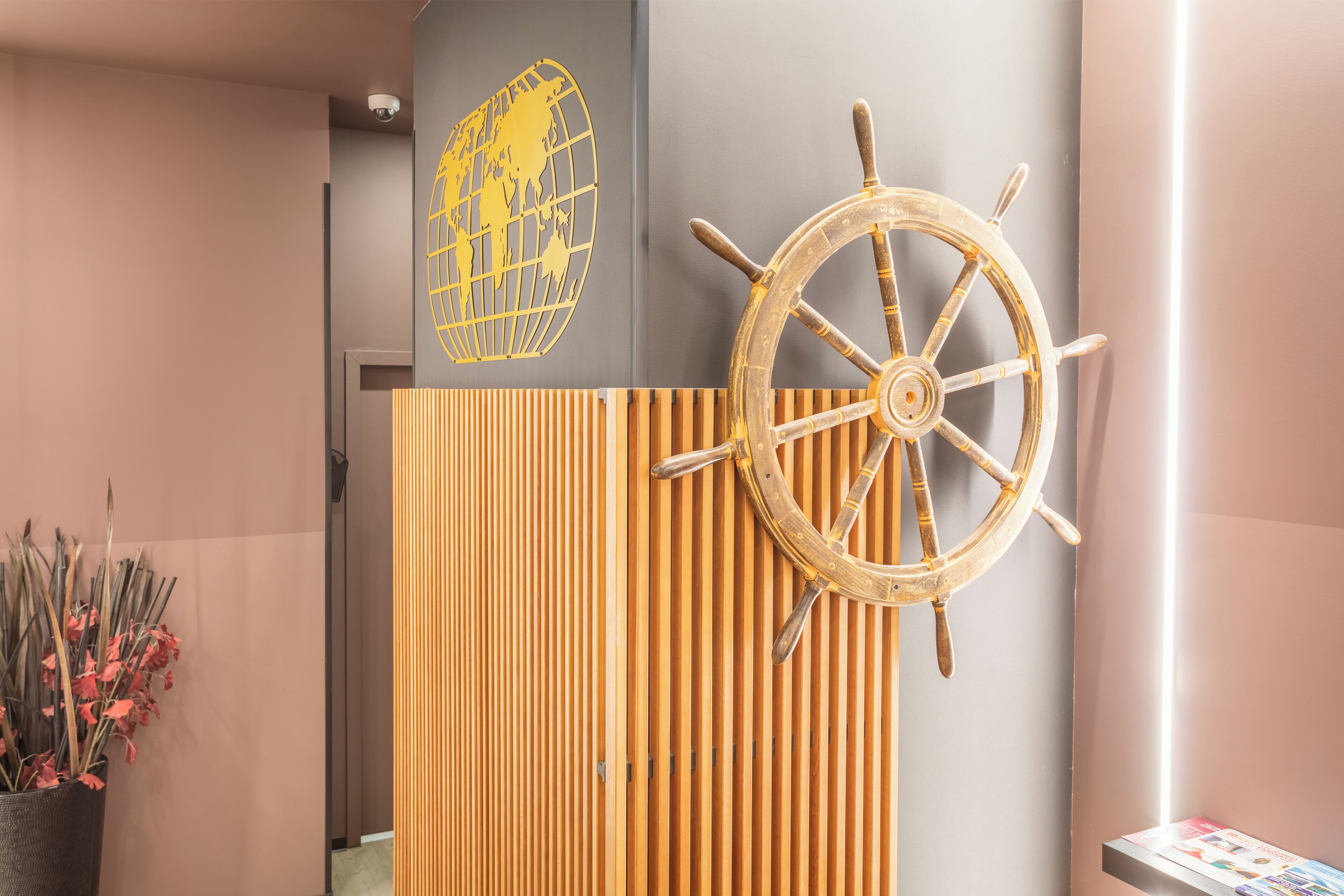 A wall with a wooden slat panel, a ship's wheel, and a world map.