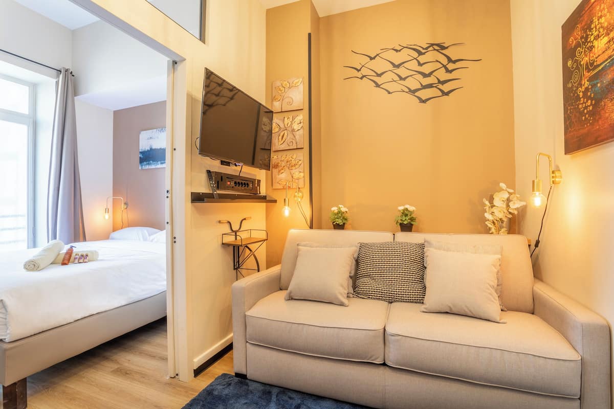 Un dormitorio moderno con cama, sofá, televisor y decoración en la pared.