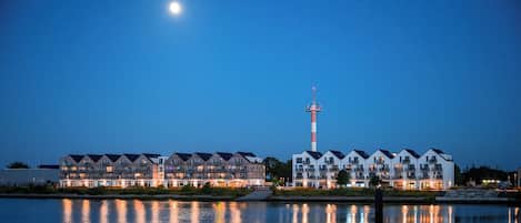 A waterfront hotel with multiple buildings, a prominent tower, and a calm reflective water surface.