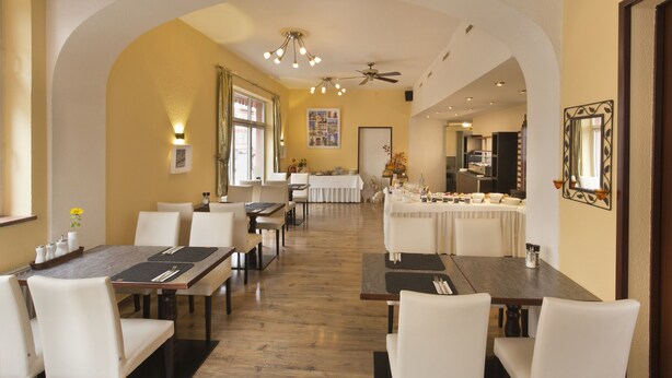 A dining area with high ceilings, chandeliers, and a central archway. Tables are set with white tablecloths and chairs. - Hotel Goldenes Lamm (Idstein)