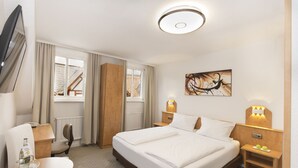 A hotel room with a bed, bedside tables, a chair, a desk, a TV, and a window with curtains. - Hotel Goldenes Lamm (Idstein)