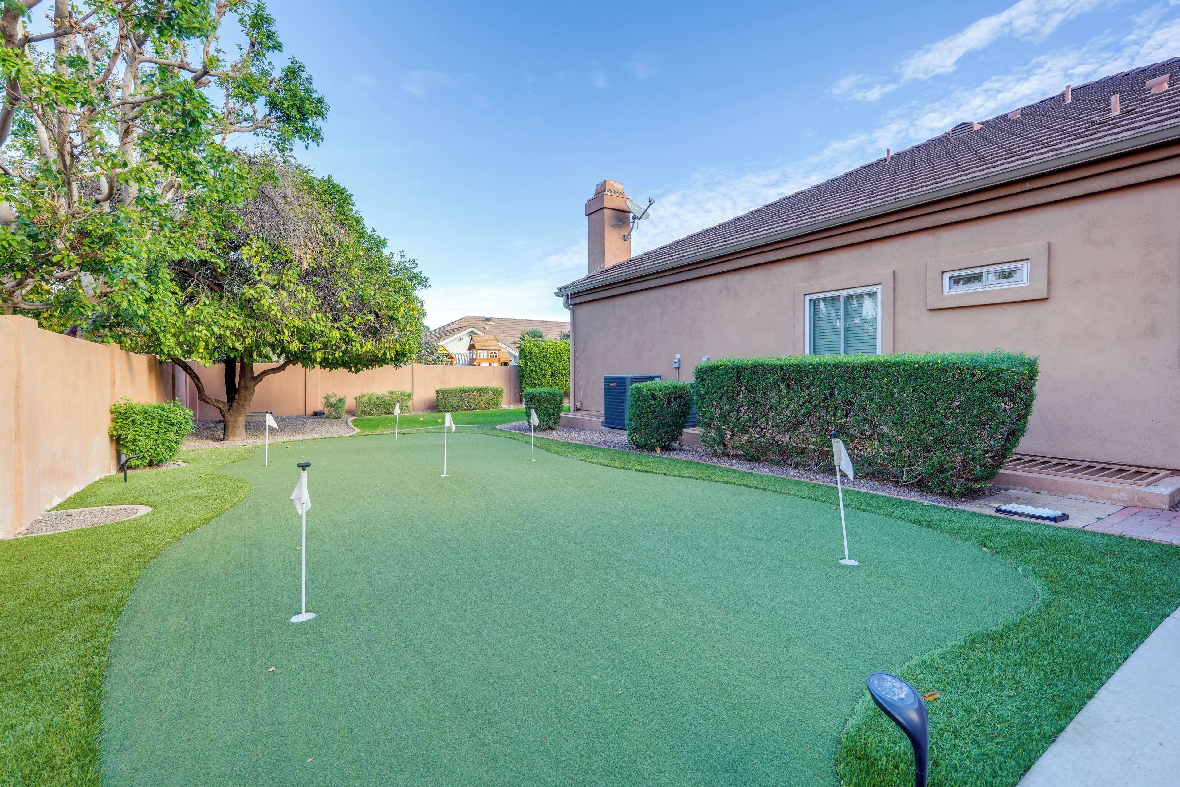 A residential property with a well-maintained lawn, a golf putting area, and a house with a chimney.