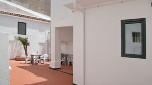 A clean, white-walled room with a tiled floor, a small table with chairs, and a potted plant.