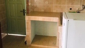 Una cocina con una puerta verde, un refrigerador blanco y paredes con azulejos.