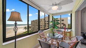 A balcony with wicker furniture, a table, and a lamp. - Endless Summer Getaway at Sandarac Fort Myers Beach (Fort Myers Beach)