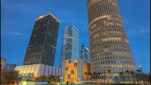 A cityscape with modern high-rise buildings, including a distinctive cylindrical building with a red top. - #9 Hideaway (Tampa)