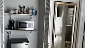 A compact kitchen with a refrigerator, microwave, and coffee maker on a white shelf. - #9 Hideaway (Tampa)