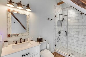 Une salle de bain avec un meuble-lavabo blanc, un grand miroir et une douche à parois de verre.