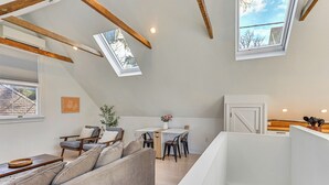 Ein Wohnbereich im Loft-Stil mit hohen Decken, Oberlichtern, einem Essbereich und einer Küche.