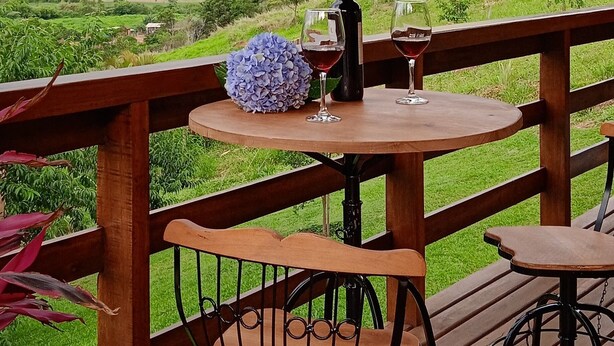 A wooden deck with a table and chairs, overlooking a hilly landscape. - Chalet in the Serra da Mantiqueira mountains in São Bento do Sapucai, near southern Minas Gerais.  (São Bento do Sapucaí)