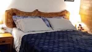 A bedroom with a wooden headboard, a blue bedspread, and two framed pictures on the wall. - Chalet in the Serra da Mantiqueira mountains in São Bento do Sapucai, near southern Minas Gerais.  (São Bento do Sapucaí)