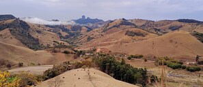 Ein weites Panorama über sanft geschwungene Hügel mit einer kleinen Siedlung, eingebettet im Tal.